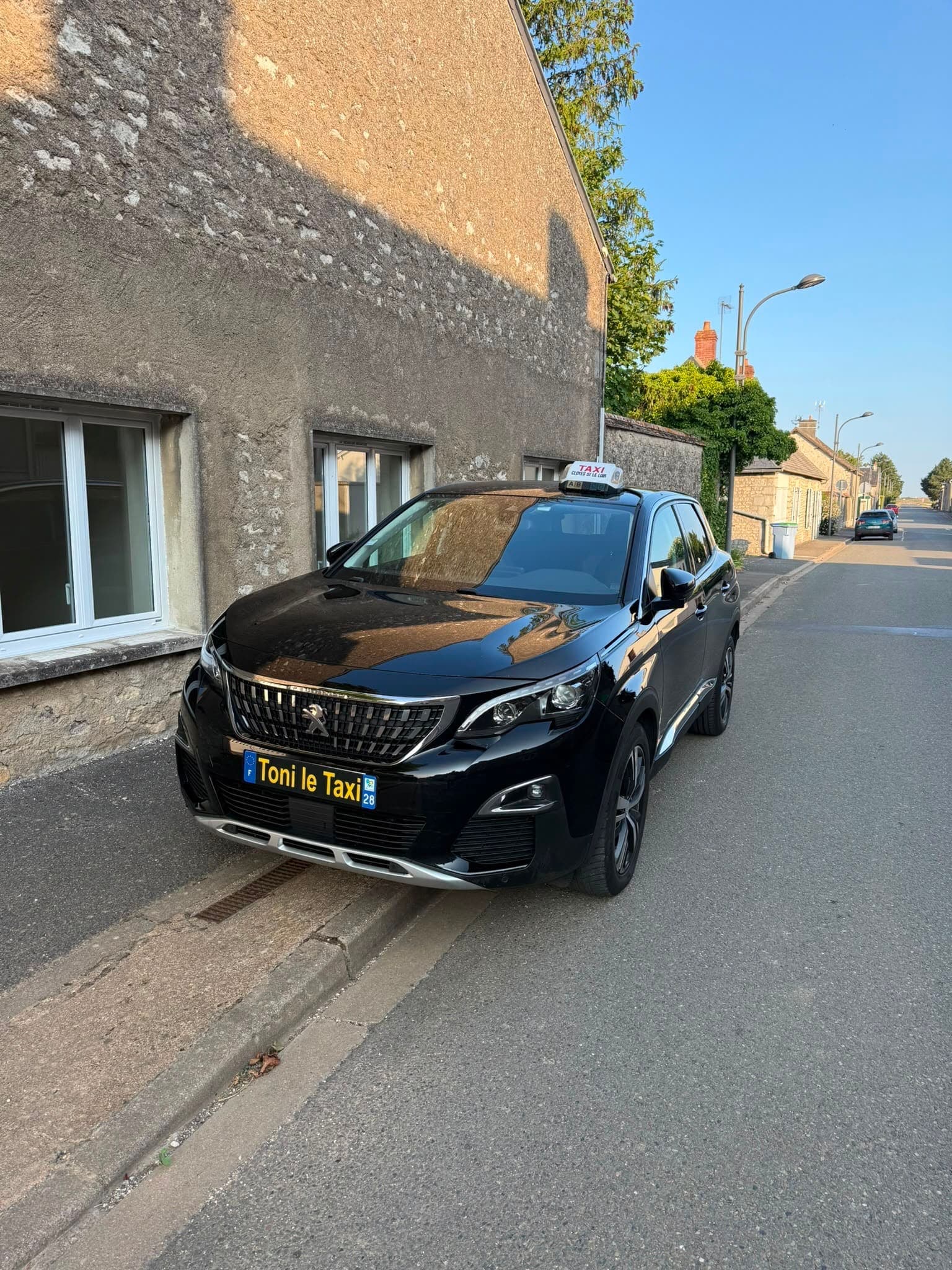 Le taxi TSM « Toni le Taxi » stationné dans une rue de village au soleil couchant